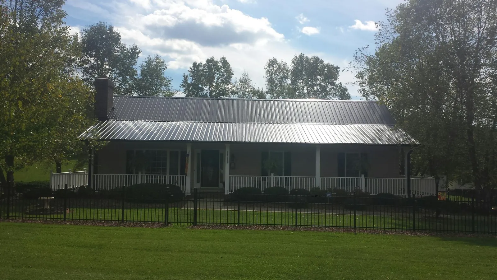 Gray metal roof on a brick ranch with a full width front porch — Gutter Guard Installation work by our crew in Wilton